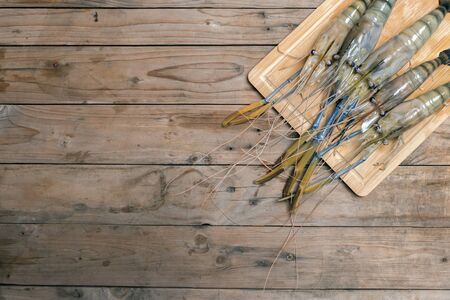 Big prawns on the wooden chopping board on the wooden tableの写真素材