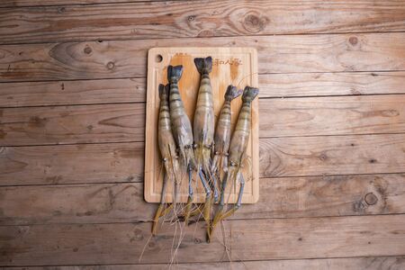 Big prawns on the wooden chopping board on the wooden tableの写真素材