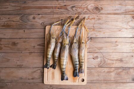 Big prawns on the wooden chopping board on the wooden tableの写真素材
