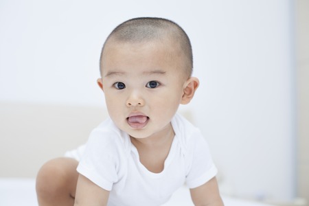 Cute Chinese baby boy crouching in bed, shot in Beijing, Chinaの写真素材