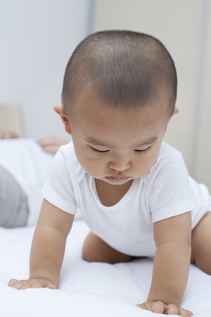 Cute Chinese baby boy playing in bed, shot in Beijing, Chinaの写真素材