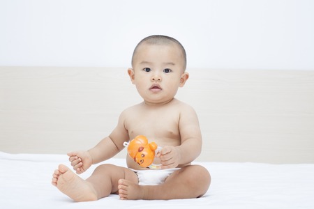 Cute Chinese baby boy sitting in bed, shot in Beijing, Chinaの写真素材