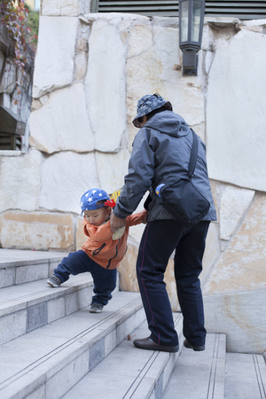 Chinese grandmother helping grandson walking on stairs, shot in Beijing, Chinaの写真素材