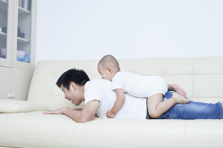 Chinese father and son playing in sofa, Beijing,Chinaの写真素材