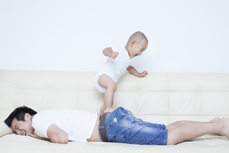 Chinese father and son playing in sofa, Beijing,Chinaの写真素材