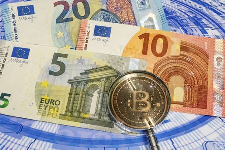 close up bitcoin coin with euro banknotes and magnifying glass on background.の写真素材