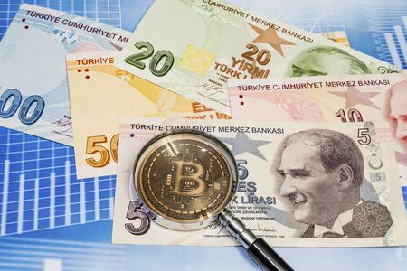close up bitcoin coin and magnifying glass with turkish lira banknotes on backgroundの写真素材