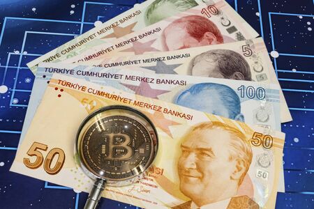 close up bitcoin coin and magnifying glass with turkish lira banknotes on backgroundの写真素材