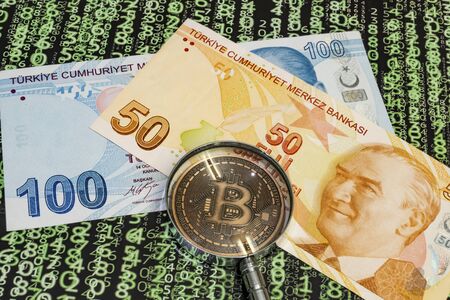 close up bitcoin coin and magnifying glass with turkish lira banknotes on backgroundの写真素材