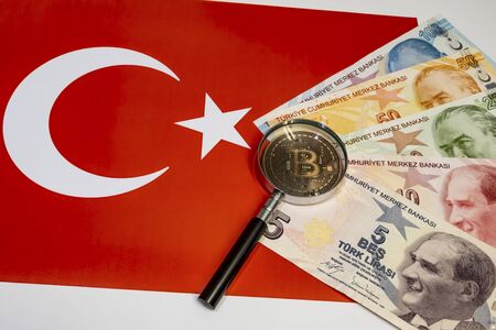 close up bitcoin coin and magnifying glass with turkish lira banknotes on backgroundの写真素材