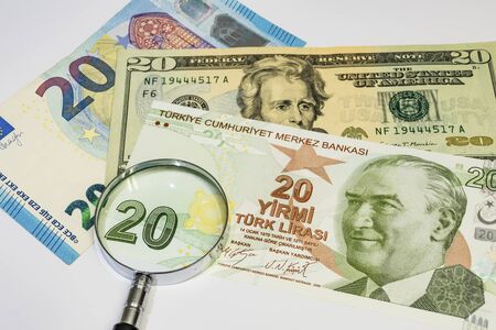 close up american dollar, turkish lira and euro banknotes with magnifying glass on white backgroundの写真素材