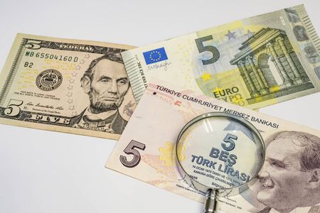 close up american dollar, turkish lira and euro banknotes with magnifying glass on white backgroundの写真素材