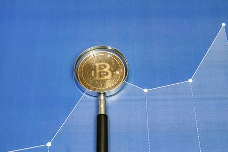 close up bitcoin coin with magnifying glass  on backgroundの写真素材