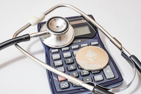 close up cryptocurrency coins on white background with calculator and stethoscope.の写真素材