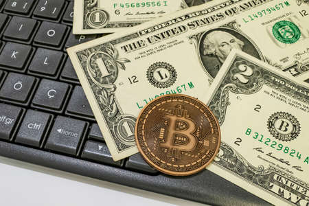 close up bitcoin coin with US dollars and computer keyboardの写真素材