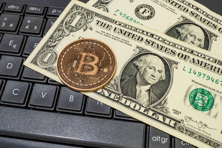 close up bitcoin coin with US dollars and computer keyboardの写真素材