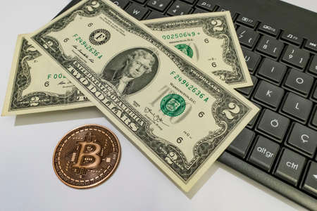 close up bitcoin coin with US dollars and computer keyboard