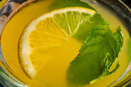 Cold lemonade in glass with lemon slice and mint leaf