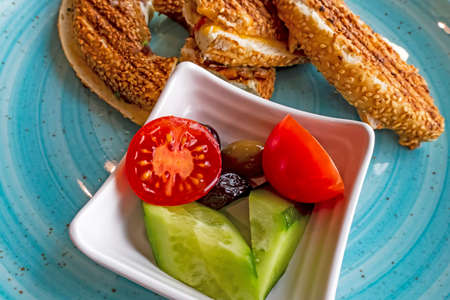 Traditional Turkish bagel. melted cheese bagel toast and tomato, cucumber and olives on plate.