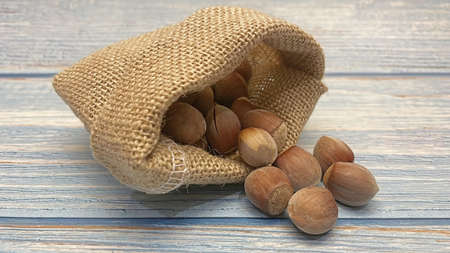 shelled hazelnuts in small wicker sack on wooden backgroundの写真素材