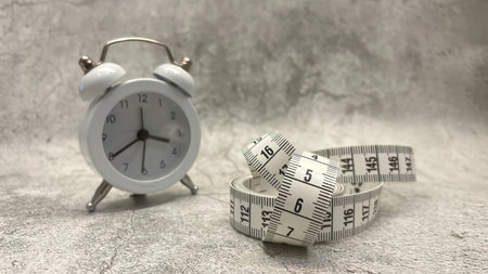 Tape measure and clock on gray floor and backgroundの写真素材