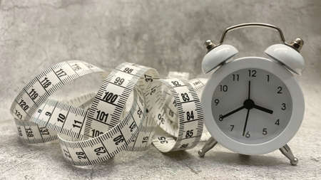 Tape measure and clock on gray floor and backgroundの写真素材