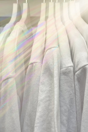 white t-shirts hanging in the closet with rainbow effectの写真素材