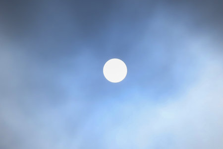 Sun in the blue sky with white clouds. The sun shines through the clouds.
