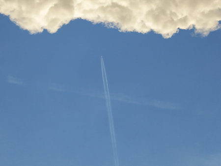 Blue sky with white clouds and airplane trailbe used as backgroundの写真素材