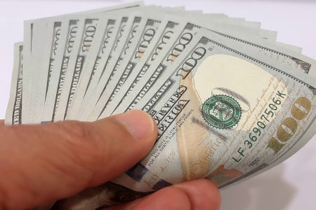Close-up of one hundred dollar bills in hand on white backgroundの写真素材