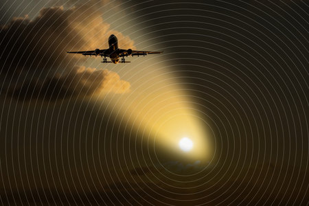 Silhouette of airplane flying into sunset sky with clouds and glowing sun. Airplane Silhouette at Sunset Sky with Glowing Sun and Clouds.の写真素材