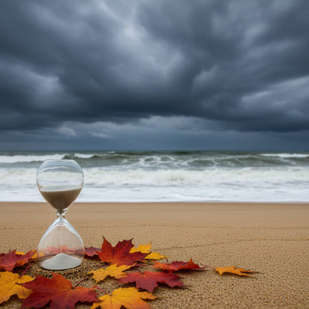 Hourglass on the beach with autumn leaves and stormy sky.の素材