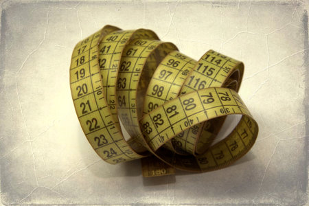Vintage measuring tape on old paper background. Retro style toned