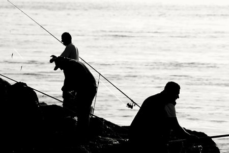 Fishermen fishing on the beach at sunset.の写真素材