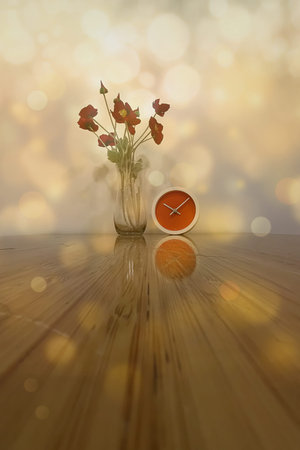Vintage clock and flowers on wooden table with bokeh background