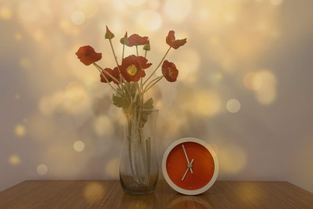 red poppies in vase and clock on wooden table with bokeh background