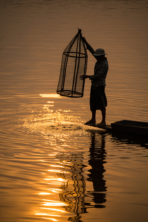 The Asian fishermanâs fishing for fishes on his boat by his equipment at the lake.のeditorial素材