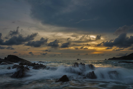 Sunset at the sea and waves on stones