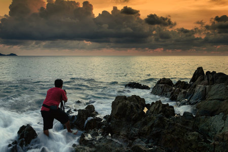 Photographer shoot the seascape on wave at sunsetの写真素材
