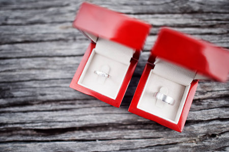 Silver wedding ring in red box on wooden background