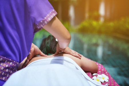 Close up hands doing back massage in spa outdoor with swimming poolの写真素材