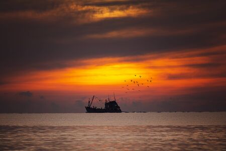Fisherman boat in a beautiful view on the sea at sunriseの写真素材