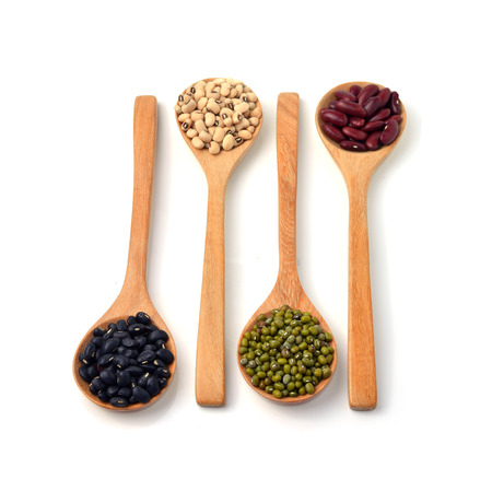 Green beans, black beans, red beans in wooden spoon, white background