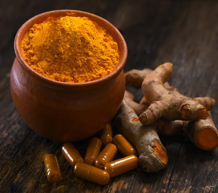 Turmeric powder and turmeric capsules on table  wooden backgroundの写真素材