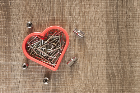 Nails with heart symbol on a wooden surface