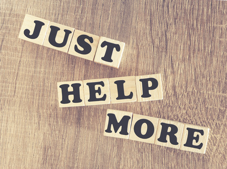 Just Help More message written with wooden blocks on a wooden table. Image cross processed for retro lookの写真素材