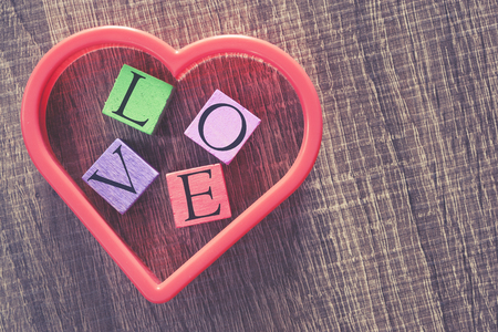 Love concept. Valentines day background with red heart and Love message written in colored wooden blocks. Cross processed image with selective focuの写真素材