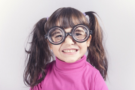Funny nerdy little girl smiling. Toned image with shallow depth of fieldの写真素材