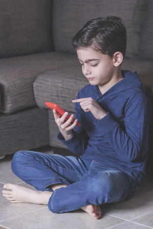 Little boy using a smart phone. Cross processed image with shallow depth of fieldの写真素材