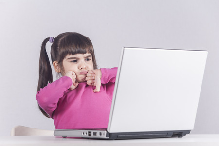 Little girl reacts while using a laptop. Internet safety concept. Toned image with selective focusの写真素材